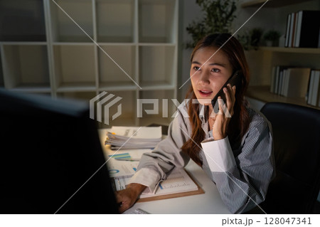 Late Night Communication. Professional woman on phone discussing financial matters. Late Night Communication. Professional woman on phone discussing financial matters. 128047341
