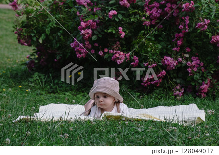 Child Lying on Blanket Surrounded by Pink Flowers Child Lying on Blanket Surrounded by Pink Flowers 128049017