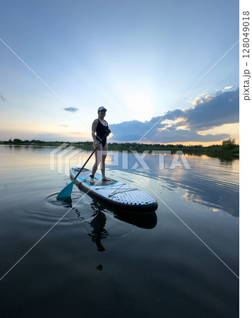 Paddleboarding at Sunset on a Tranquil Lake 128049018
