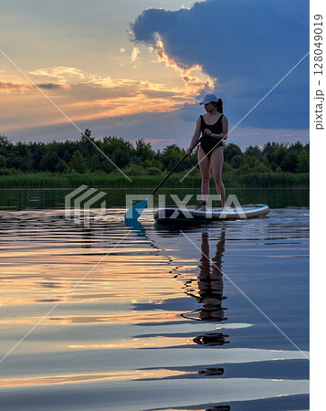 Paddleboarding at Sunset on a Tranquil Lake 128049019