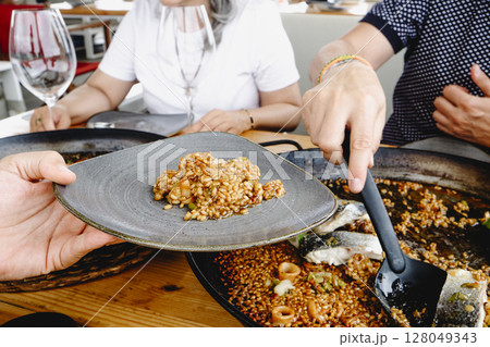 serving seafood rice from a paella pan 128049343