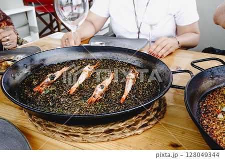 black rice with prawns in a paella pan 128049344
