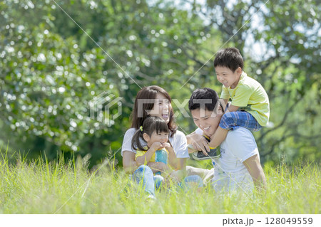 公園の草地で遊ぶ4人家族 128049559