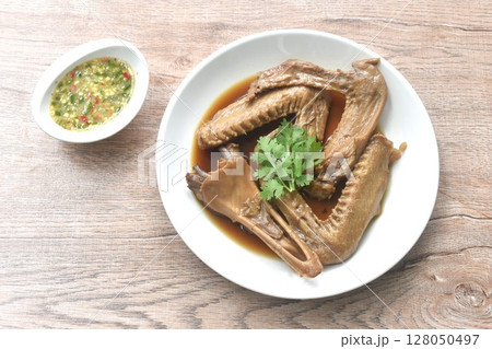 chop boiled duck wing and beak with tongue stew in brown soy soup on plate dipping spicy sour chili sauce  128050497