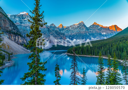 象徴的なモレーン湖の日の出、テンピークスに射す朝焼けの光。カナダ、アルバータ州、バンフ国立公園 象徴的なモレーン湖の日の出、テンピークスに射す朝焼けの光。カナダ、アルバータ州、バンフ国立公園 128050570