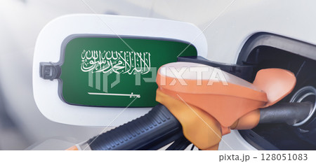 The flag of Saudi Arabia on the lid of the gas tank of a car at a gas station in close-up. High or low gasoline prices at Saudi gas stations. In Saudi Arabia, gasoline prices are rising due to a The flag of Saudi Arabia on the lid of the gas tank of a car at a gas station in close-up. High or low gasoline prices at Saudi gas stations. In Saudi Arabia, gasoline prices are rising due to a 128051083