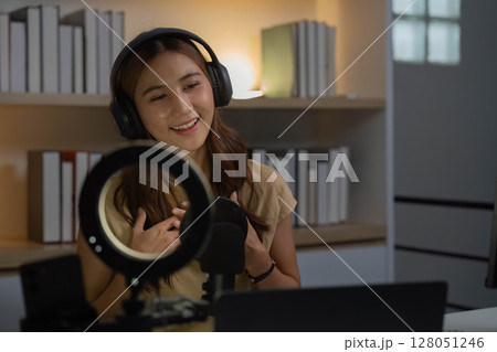 Remote Work and Digital Communication. Young woman engaging in virtual meeting with headphones. 128051246