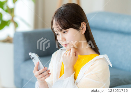 スマホを見て考える若い女性 128051736