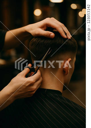 a guy gets his hair cut at a barbershop a guy gets his hair cut at a barbershop 128053142