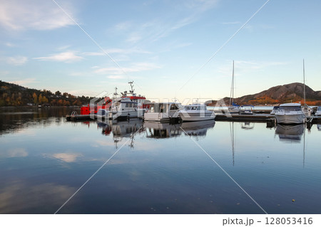 Reflection of moored boats in tranquil waters at a scenic Norwegian marina 128053416