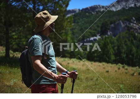 Man Hiking in a Scenic Mountain Landscape Wearing Outdoors Attire Man Hiking in a Scenic Mountain Landscape Wearing Outdoors Attire 128053796