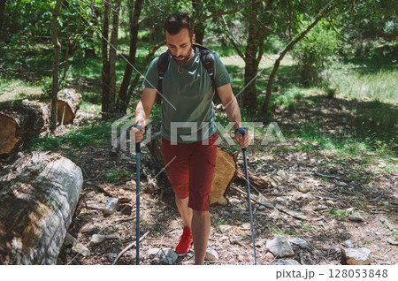 Bearded Man Hiking in a Forested Mountain Area with Trekking Poles Bearded Man Hiking in a Forested Mountain Area with Trekking Poles 128053848