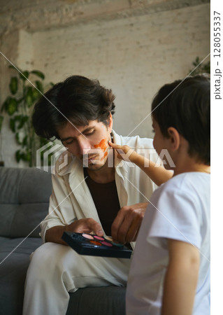 Playful fatherhood. Father and son enjoying playful face painting bonding 128055337