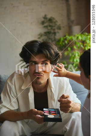 Playful fatherhood. Father and child bonding over playful makeup session at home 128055346