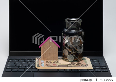 ノートパソコンと一万円札と家型の模型と瓶に入った小銭 128055995