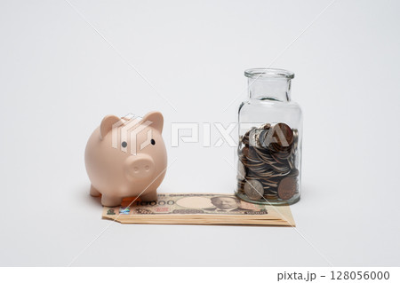 ガラス瓶に入ったコインと新紙幣と豚の貯金箱 128056000