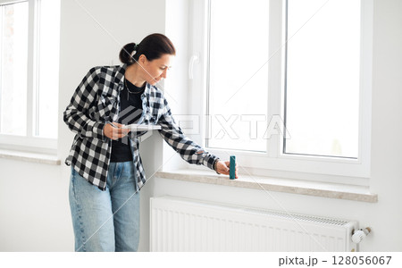 Girl Uses A Laser Measure To Check Window Dimensions For Room Renovation 128056067