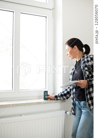 Girl Using Laser Measure On Window In White Empty Room 128056070