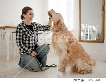 Cute Girl Petting Adorable Golden Retriever Dog On The Kitchen Floor Cute Girl Petting Adorable Golden Retriever Dog On The Kitchen Floor 128056090