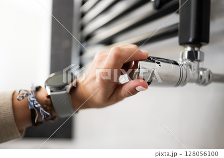 Female Hand Adjusts The Temperature Of The Radiator of Towel Warmer In The Bathroom Female Hand Adjusts The Temperature Of The Radiator of Towel Warmer In The Bathroom 128056100