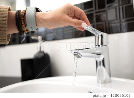 Girl Opens The Bathroom Sink Mixer Tap And Water Flows From The Faucet 128056102
