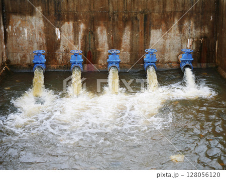 Industrial drainage system with five blue pipes discharging water into a reservoir. Concept of water management, wastewater treatment, and environmental engineering, spillway Industrial drainage system with five blue pipes discharging water into a reservoir. Concept of water management, wastewater treatment, and environmental engineering, spillway 128056120