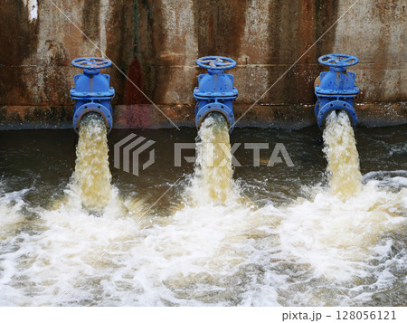 Industrial drainage system with five blue pipes discharging water into a reservoir. Concept of water management, wastewater treatment, and environmental engineering, spillway 128056121