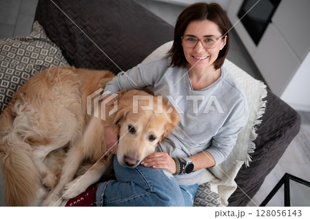 Happy Woman Hugging An Adorable Dog Relaxes On The Sofa At Home Happy Woman Hugging An Adorable Dog Relaxes On The Sofa At Home 128056143