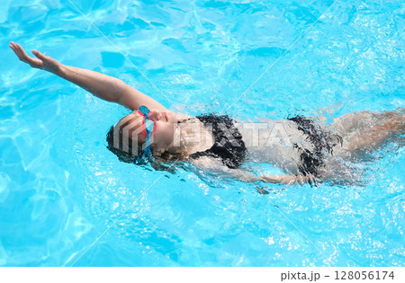 Young Girl Swims Backstroke In Outdoor Pool 128056174