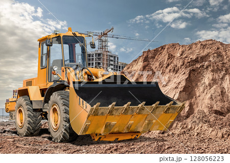 Construction machinery operating at a building site during daylight Construction machinery operating at a building site during daylight 128056223