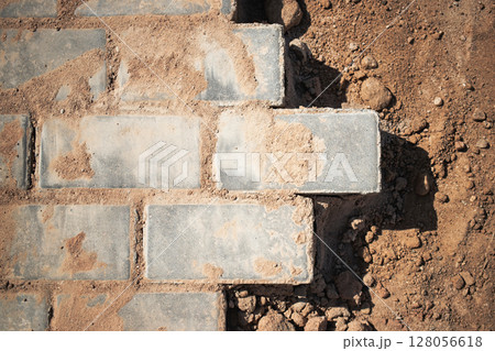 Brick pathway under construction in sunny environment with scattered dirt and gravel nearby Brick pathway under construction in sunny environment with scattered dirt and gravel nearby 128056618