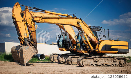 Heavy machinery excavator working on construction site during sunny day with clouds Heavy machinery excavator working on construction site during sunny day with clouds 128056632