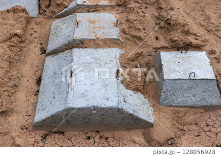 Reinforced concrete foundation of a modern monolithic residential building. Prepared formwork with reinforcing mesh for pouring concrete. Dirt and clay at the construction site. 128056928