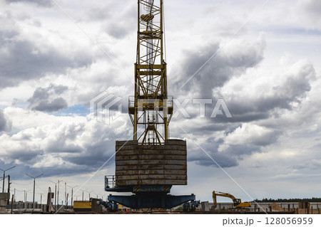 Tower crane close-up against the background of the cloudy sky. Modern building technologies. Tower crane close-up against the background of the cloudy sky. Modern building technologies. 128056959