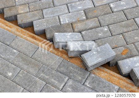 Pavement repairs and paving slabs laying on the prepared surface, with tile cubes in the background. Laying paving slabs in the pedestrian zone of the city. Paving slabs and curbs. 128057070