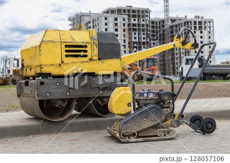 Vibratory rammer with vibrating plate on a construction site. Manual roller. Compaction of the soil before laying paving slabs. close-up. 128057106
