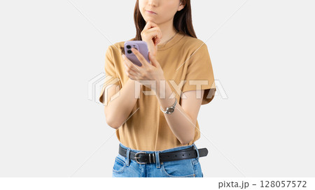 スマートフォンを見て考える若い女性 128057572