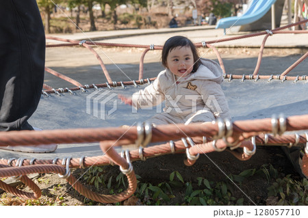 【相模原市立麻溝公園の子どもの広場のトランポリンでママと遊ぶ1歳児】 【相模原市立麻溝公園の子どもの広場のトランポリンでママと遊ぶ1歳児】 128057710