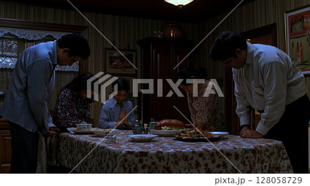 A family of five is gathered around a table with a turkey on it 128058729