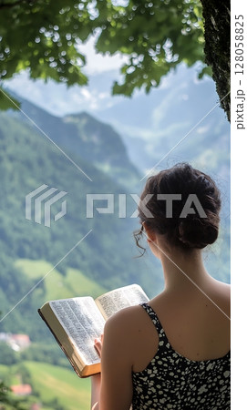 A woman is reading a book while looking out over a mountain 128058825