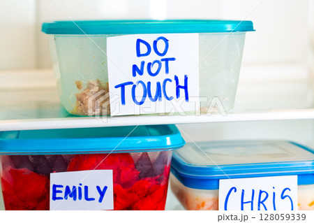 Do Not Touch sticker on lunch boxes in office refrigerator. Angry and hungry workers concept. 128059339