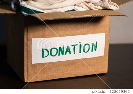 Cardboard box full of clothing ready for donation. Modern eco friendly habits and conscious consumption. Zero waste. Cardboard box full of clothing ready for donation. Modern eco friendly habits and conscious consumption. Zero waste. 128059366