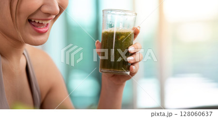 Enjoying Nutrition. Woman savoring a green smoothie in a glass. 128060637