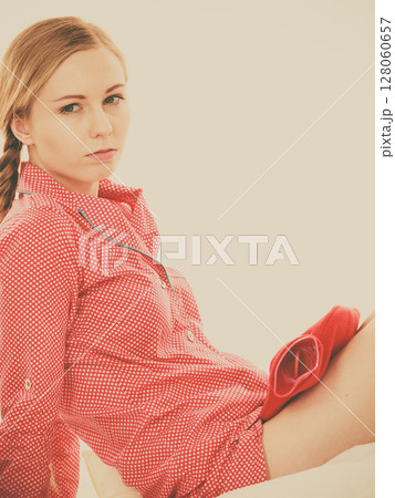 Woman feeling stomach cramps lying on bed 128060657