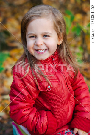 Little girl holding yellow autumn leaves, smiling outdoor park. Seasonal joy child happiness concept 128061352