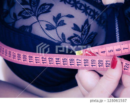Woman measuring her chest breasts bust size 128061587