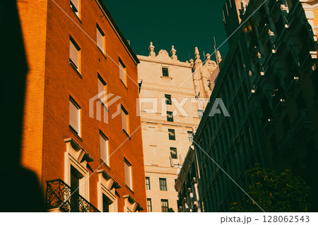 Facades of orange, beige buildings in different architectural styles against dark blue sky. Eclectic with modern and vintage high-rise buildings. 128062543