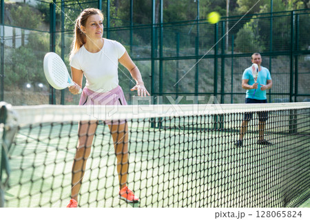 European woman padel tennis player trains on the outdoor court European woman padel tennis player trains on the outdoor court 128065824