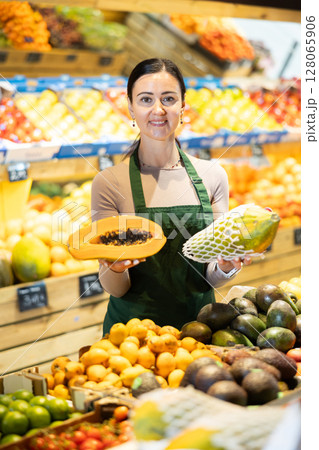 Middle-aged female seller offering papaya in grocery market 128065906