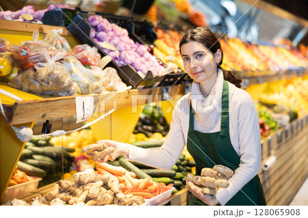 Woman seller laying out ginger on the counter 128065908